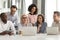 Smiling mature mentor teaching diverse employees team, using laptop