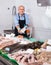 Smiling mature salesman with apron offering fresh fish