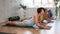 Smiling mature woman doing cobra pose of yoga on black mat in light training room