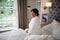 Smiling mature woman sitting in illuminated bedroom at home