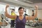 Smiling mature women showing her strength after workout in the gym, arms raised and flexing muscles