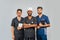 Smiling medical team standing together over light gray background. African American nurse and two Indian doctors