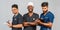 Smiling medical team standing together over light gray background. African American nurse and two Indian doctors