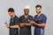 Smiling medical team standing together over light gray background. African American nurse and two Indian doctors