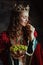 smiling medieval queen in red dress with plate of grapes