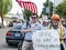 Smiling men hold flag at `Hate not a family value` sign at rally