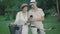 Smiling mid-adult man and woman standing in park with bikes and using smartphone. Portrait of happy loving Caucasian