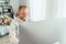 Smiling Middle-aged man in eyeglasses using a modern computer in his living room. Writing or Distance or freelance work on