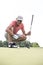 Smiling middle-aged man looking at ball while crouching on golf course