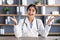 Smiling millennial attractive indian woman doctor in white coat gesturing and talking at workplace in clinic