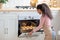 Smiling Millennial Female Baking Croissants In Oven At Home