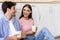 Smiling millennial woman and guy with cups of hot drink sitting on floor and talking, lady flirting