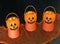 Smiling mini Halloween jack-o-lanterns holding colorful candy corn, on a black and orange backdrop.