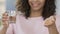 Smiling mixed race female holding multivitamin supplements and glass of water