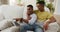 Smiling mixed race gay male couple sitting on sofa looking at laptop and talking