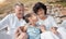 Smiling mixed race grandparents sitting with granddaughter on a beach. Adorable, happy, hispanic girl bonding with