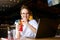 Smiling mixed race woman with cocktail in hand works with laptop. Businesswoman in glasses drinks juice for body