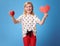 Smiling modern child showing paper heart and an apple on blue