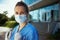 Smiling modern physician woman in scrubs outdoors near clinic