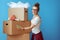 Smiling modern woman signs cardboard box on blue