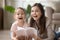 Smiling mom and daughter lying on floor reading book together