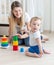 Smiling mother assembling toy pyramid with her baby boy