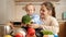 Smiling mother with baby boy playing and singing songs with vegetables and fruits on kitchen. Concept of little chef, children