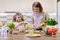 Smiling mother and daughter 8, 9 years old cooking together in kitchen vegetable salad. Healthy home food, communication parent
