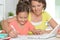 Smiling mother and daughter doing homework with help of laptop together
