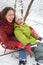 Smiling mother, daughter pose on sled