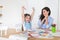 Smiling mother and daughter preparing for lessons and draws at the table with pencils and paints. Parent and pupil of preschool.