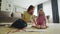 Smiling mother and daughter sit in the hall on the floor and draw together. Preparation for art school. Mom friendly