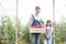 Smiling mother and daughter with tomato crate at greenhouse