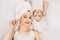 Smiling mother and daughter in towels at bathtime. Young Caucasian woman mom with her little girl toddler, lying