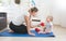 Smiling mother doing physical exercise with her baby on floor at