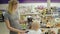 Smiling mother showing her child a toy elephant in a toy section for children in the supermarket while her cute little