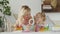 Smiling mother smiles at curly haired blonde daughter child, preschool learning activity at home, concept of healthy growing,