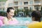 Smiling mother and son floating on inflatable tubes and playing in the pool