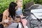 smiling mothers sitting on bench near baby strollers with coffee in paper cup