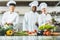 smiling multicultural chefs at restaurant kitchen with vegetables