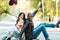 Smiling multicultural couple sitting on a longboard on a street and rising hands