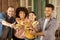 Smiling multiethnic friends holding burgers at picnic on patio