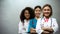 Smiling multiracial doctors with red ribbons, international AIDS awareness sign