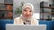 Smiling Muslim female business freelancer working laptop browsing internet at home couch closeup