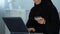 Smiling muslim female inserting credit card number on laptop, shopping online