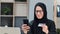 Smiling Muslim woman use smartphone application online shopping card payment goods from internet