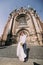 Smiling newlywed couple dancing and hugging near old gothic christian cathedral