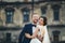 Smiling newlyweds hug in the front of an old castle