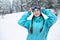 Smiling nordic woman with pigtails puts on protective ski goggles. Snowboarder girl touching mask at ski resort on