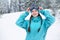 Smiling nordic woman with pigtails puts on protective ski goggles. Snowboarder girl touching mask at ski resort on